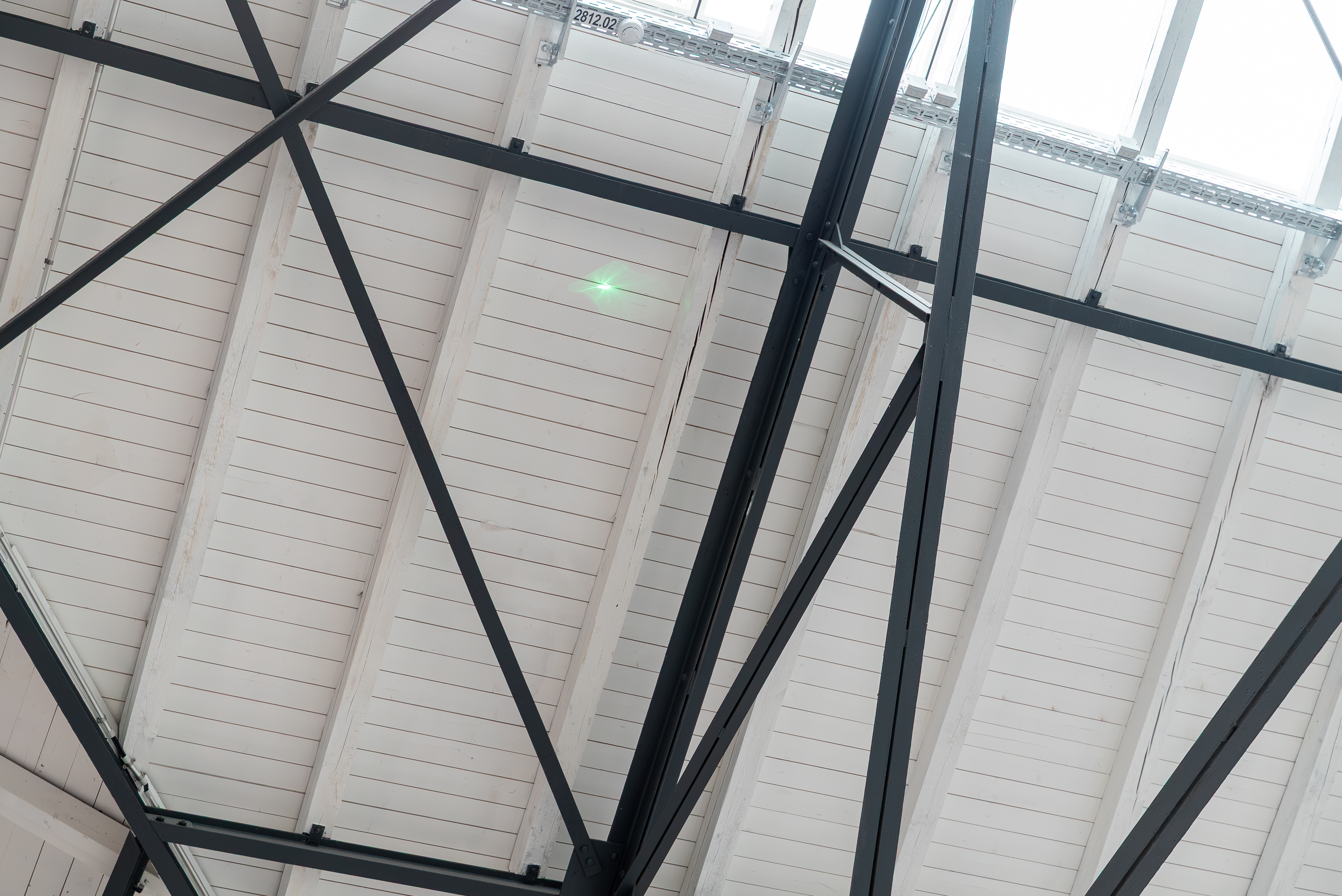 Grüner Laserpunkt eines Indoor Lasers an der Decke einer Halle